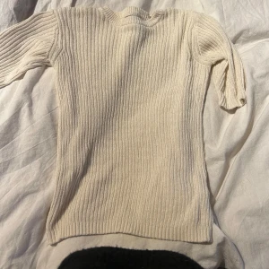 Beige ribbad tröja från Carin Wester - Säljer en stilren beige ribbad tröja från Carin Wester. Tröjan har en klassisk design med korta ärmar och rund halsringning. Perfekt för en avslappnad och trendig look.