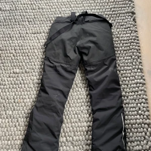 Svarta skidbyxor från Everest, strl 170 - Säljer ett par svarta täckbyxor från Everest med hängslen och dragkedjor vid fickorna. Perfekta för vintern med TCS Waterproof-teknologi som håller dig torr. Byxorna har en praktisk design med justerbar midja för bästa passform. Fint skick, används 2 veckor. Strl 170