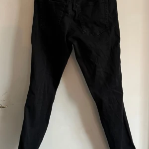 Svarta jeans från Diesel - Snygga svarta jeans från Diesel med klassisk design. De har en normal passform och är perfekta för en stilren look. Jeansen har en knappgylf och flera fickor för praktisk användning. Passar stl 152 - W26 L30