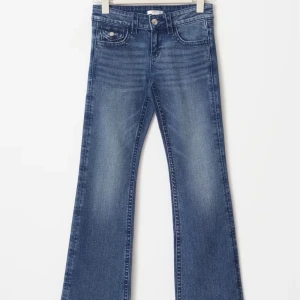 Blå bootcut jeans - Snygga blå bootcut jeans med klassisk femficksdesign och knappgylf. Perfekta för en avslappnad stil med en touch av retro. Passar bra till både sneakers och klackar.