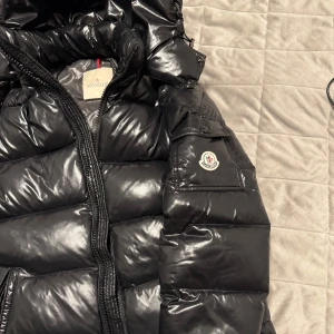  Moncler Jackan - Säljer en snygg svart dunjacka från Moncler. Perfekt för kalla dagar med sin pufferdesign som håller dig varm och stilren.