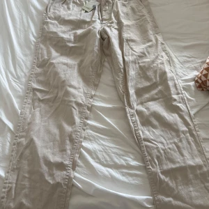 Beige linnebyxor från Livergy - Säljer ett par bekväma beige linnebyxor från Livergy. Byxorna har en avslappnad passform med elastisk midja för extra komfort. Perfekta för varma dagar med sitt lätta och luftiga material.