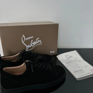 Svarta sneakers från Christian Louboutin - Snygga svarta sneakers från Christian Louboutin med den ikoniska röda sulan. Skorna har en stilren design med snörning och är perfekta för en trendig look.