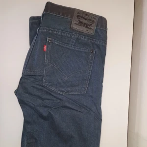 Levi's jeans  - Snygga mörkblå Levi's jeans med klassisk femficksdesign och en extra dragkedja på bakfickan. Kostade ca 1500 kr vid inköp. Garderobsrensning så kika gärna på övriga auktioner.