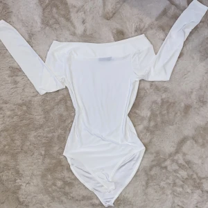 Vit offshoulder topp från Boohoo - Säljer en stilren vit offshoulder topp från Boohoo. Toppen har långa ärmar och är tillverkad i ett mjukt och stretchigt material. Perfekt för en elegant look.