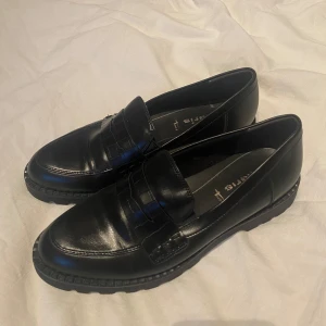Svarta loafers - Snygga svarta loafers i skinn med en klassisk design. Skorna har en robust sula och en stilren look som passar perfekt till både vardag och mer uppklädda tillfällen.