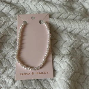 Pärlhalsband från Nova & Hailey - Elegant pärlhalsband från Nova & Hailey med vita pärlor och ett justerbart guldfärgat lås. Perfekt för att ge en klassisk touch till din outfit.