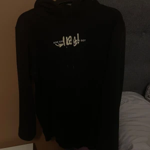 Svart hoodie med tryck - Säljer en svart hoodie med texttryck på framsidan och baksidan från hm. Perfekt för en avslappnad stil. Hoodien har en klassisk passform med långa ärmar och en bekväm huva. Tröttnat och använder ej den längre, storlek S men passar även M