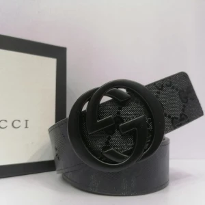 Svart bälte från Gucci - Snyggt svart bälte från Gucci med det ikoniska GG-mönstret och en stor rund spänne. Perfekt för att ge en lyxig touch till din outfit. Bältet är tillverkat i ett elegant material som ger en exklusiv känsla.