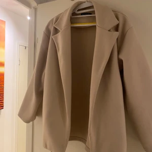 Beige kappa från Zara - Snygg beige kappa från missäy med en stilren design. Jackan har långa ärmar och en klassisk krage. Perfekt för att hålla stilen under kyligare dagar. Passar bra till både vardag och mer uppklädda tillfällen. Köpte den nyligen men har ej använt den 