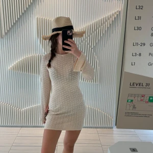 Beige stickad strandklänning - Säljer en snygg beige stickad klänning med lång ärm och öppen rygg. Perfekt över en bikini. Klänningen är kort och har en tight passform. Perfekt för både sommar och vår!