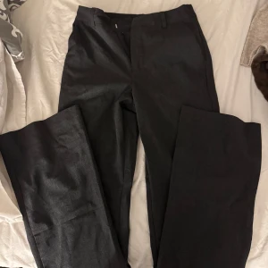 Grå kostymbyxor från BikBok - Snygga grå kostymbyxor från BikBok i en klassisk stil. Byxorna har en rak passform och är perfekta för en stilren look. De har en diskret dragkedja och knapp framtill. Det är storlek 34 men sitter mer som 36