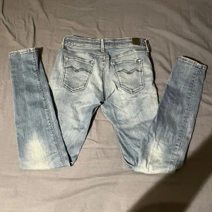 Blå jeans från Replay - Snygga blå jeans från Replay med en klassisk femficksdesign och ljusa tvättade detaljer. De har en knappgylf och är perfekta för en avslappnad stil. Märkeslogga på baksidan av midjan. Dåliga bilder 
