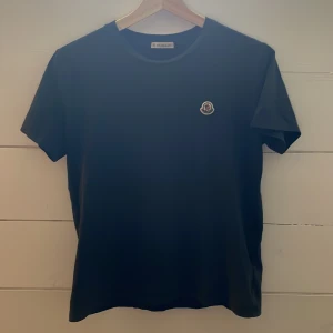 Mörk blå t-shirt från Moncler - Snygg svart t-shirt från Moncler med korta ärmar och en broderad logga på bröstet. Perfekt för en stilren look.