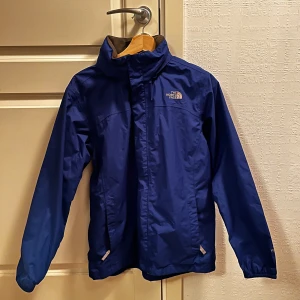 vindjacka från The North Face - Säljer nu denna blå vindjacka från The North Face med dragkedja och hög krage med inbyggd luva|, skick 9/10✅| Perfekt för blåsiga dagar och äventyr utohus. Köpt för 1300kr