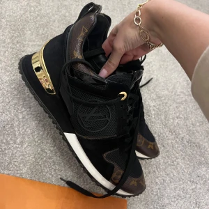Svarta sneakers från Louis Vuitton - Snygga svarta sneakers från Louis Vuitton med guldiga detaljer och klassiskt monogrammönster. Skorna har snörning och en kombination av olika material som ger en lyxig känsla. Perfekta för den stilmedvetna. Självklart äkta, kvitto finns 🩷