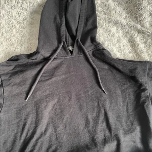 Svart hoodie från Even&Odd - Säljer en stilren svart hoodie från Even&Odd. Den har en klassisk design med dragsko i huvan och är perfekt för en avslappnad look. Passar bra till både jeans och mjukisbyxor.