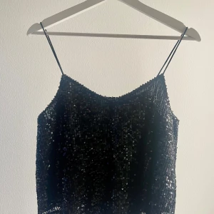 Svart paljettlinne från Bik Bok - Snyggt svart linne från Bik Bok täckt med glittrande paljetter. Linnet har tunna axelband och en elegant design som passar perfekt för festliga tillfällen. Perfekt för att lysa upp kvällen! ✨använd fåtal gånger!