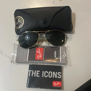 Solglasögon från Ray-Ban - Snygga Ray-Ban solglasögon med klassisk aviator-stil. De har en elegant guldfärgad metallram och mörka linser. Perfekt för en stilren look. Levereras med originalfodral och putsduk. Helt nya, använd max 2 gånger.