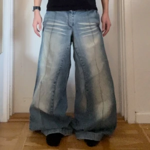 Blå 2000s jeans  - Säljer ett par blå 2000s jeans med en avslappnad passform. De har en ljus tvätt som ger en vintagekänsla med dubbel knapp. Byxorna är i bra skick men det finns ett litet hål vid knät, o lite heal bite men annars är byxorna i perfekt skick! Midjemåttet är 39cm rakt över, benlängd är ca 102cm, ben öppning 16cm :)