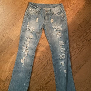 Blå slitna jeans - Säljer dessa supersnygga jeans med hål då dem tyvärr var för små för mig. Dom är i storlek 36. Dom är även insydda lite i midjan. Midjemått: 35cm rakt över Innerbenslängd: 74 cm