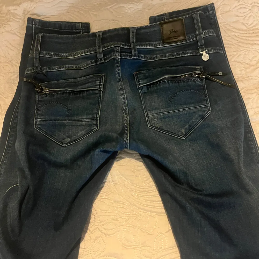 Snygga mörkblå jeans med en tight passform och coola dragkedjedetaljer på bakfickorna. Jeansen har en klassisk femficksdesign och är perfekta för en stilren look. Skriv vid frågor eller intresse💕💕. Farkut & Housut.