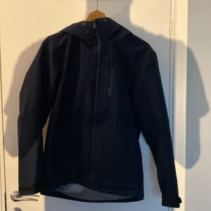 Regnjacka från Sail Racing - Snygg mörkblå jacka från Sail Racing med huva. Den är i 9/10 ✅ riktigt fett! Den  är tyvärr för lite för mig och det är derför jag säljer den. Den kostar 2999 ny och är en skaljacka!