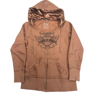 Hoodie från Enjoy - Snygg brun hoodie från Enjoy med ett coolt tryck på framsidan. Hoodien har en dragkedja och fickor med coola detaljer framtill samt en fodrad luva. 