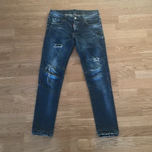 Mörkblå jeans från Dsquared2 - Snygga mörkblå jeans från Dsquared2 med slitna detaljer och en klassisk femficksdesign. Jeansen har en slim fit passform och är perfekta för en avslappnad stil. Märkeslogga på baksidan och vid fickan ger en extra touch. Pris kan diskuteras!!! 