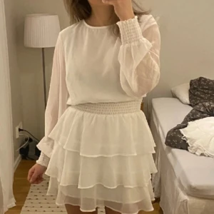 Studentklänning - Jättefin vit långärmad volang klänning / studentklänning! Topp skick förutom att knappen lossnat, se bild 2 (lätt att sy fast igen)🥰 Passar så bra nu till studentet.