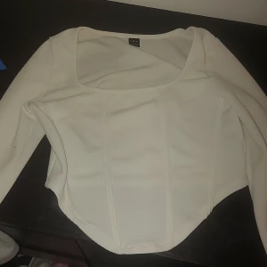 Vit topp från SHEIN - Säljer en stilren vit topp från SHEIN med långärmad design. Toppen har en fyrkantig urringning och en figurnära passform som ger en elegant look. Perfekt för att matcha med både jeans och kjol.