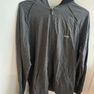 Grå Hugo boss tröja 🩶 - Säljer en stilren grå hoodie från Boss med dragkedja framtill. Funkar både att träna i och ha till vardags! 
