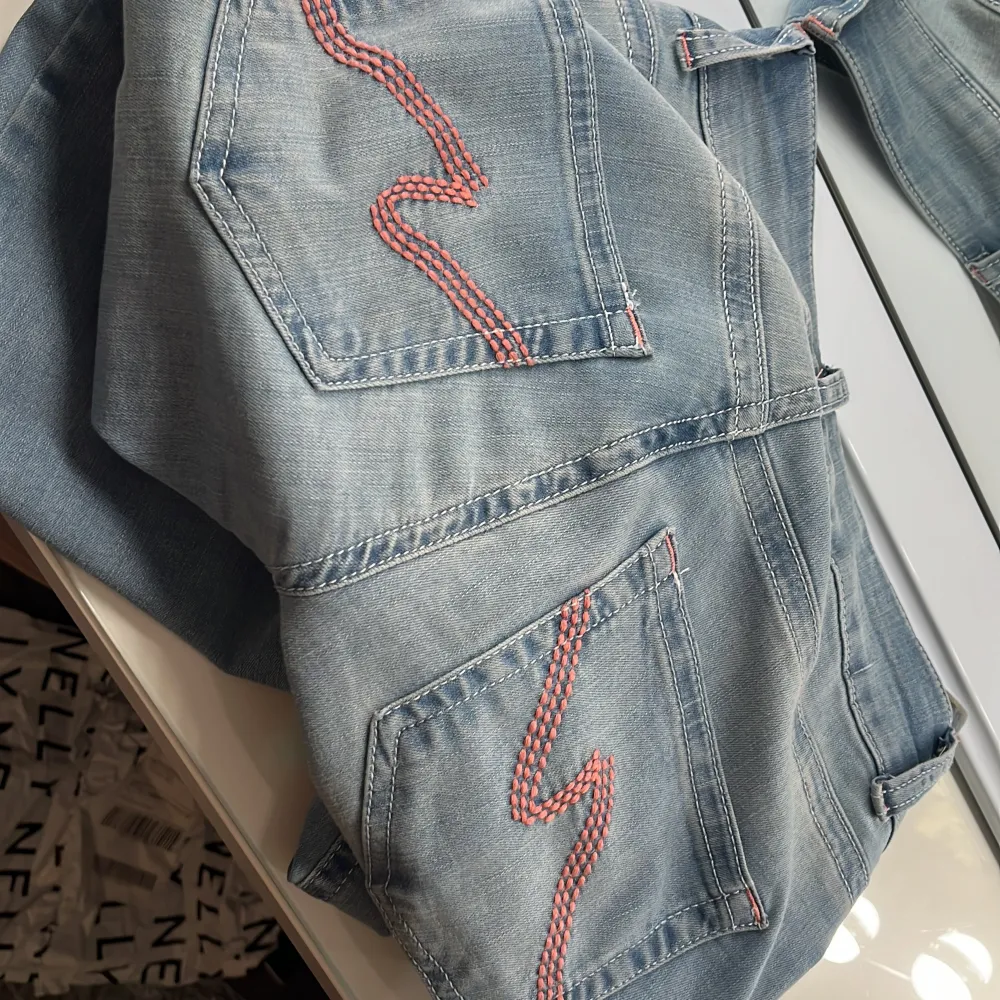 Jag säljer dessa jätte snygga ljusblå bootcut jeans från Nelly med låg midja. De har rosa broderade detaljer på bakfickorna. Jag har lappen kvar men avdragen, så kan inte returnera dom. Bara testade, inga defekter eller skador. Säljer på grund av att de är för långa🩷 Köpta för 699kr💞 skriv för mer bilder💓. Farkut & Housut.