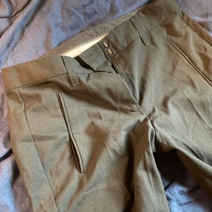 Low waisted svarta kostymbyxor - Snygga svarta low waisted kostymbyxor med dragkedja och knappar. De har en klassisk design med fickor fram och bak. Perfekta för en stilren look.