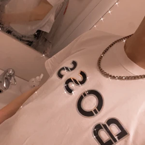 Vit t-shirt från Boss - Vit t-shirt från Boss med svart och grön logotyp på bröstet. Perfekt för en stilren och avslappnad look.