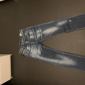 Blå jeans från Dsquared2 med slitningar  - Snygga blå jeans från Dsquared2 med slitna detaljer och en cool tvätt. De har en klassisk femficksdesign och en tydlig logga på baksidan. Perfekta för en avslappnad stil med en touch av edge. Det är storlek 48 vilket är ungefär samma som 32. Är 185 och passar mig bra 