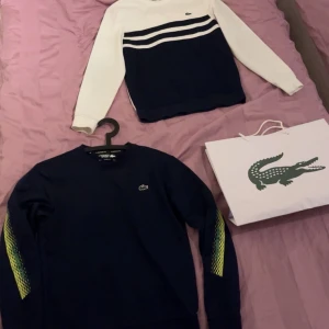 Lacoste tröjor  - Säljer två snygga Lacoste tröjor. Den ena är vit med blå ränder över bröstet och den andra är mörkblå med gröna detaljer på ärmarna. Båda har den klassiska krokodilloggan på bröstet. Perfekta för en stilren look! Köpte för 3000kr sammanlagt på lacoste hemsida. Båda är i storlek S och är i ett mycket bra skick. Obs säljer båda i ett köp!