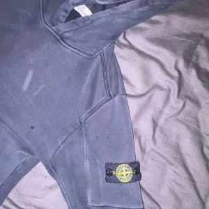 Mörkblå/ svart hoodie från Stone Island Junior - Säljer en mörkblå hoodie från Stone Island Junior. Tröjan är rätt så sliten men säljer därför för väldigt billigt, ett håll finns på armbågen men går att sy ihop ifall man orkar. Hoodien är ganska liten!! Pris kan diskuteras 