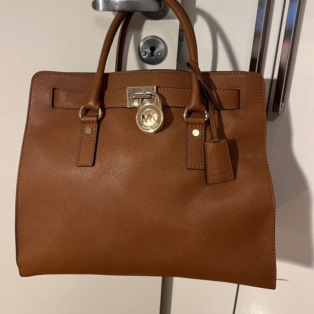 Säljer en super snygg brun handväska från Michael Kors i mycket bra skick. Väskan har eleganta gulddetaljer och både ett kortaste och längre handtag. Den är lagom stor och har plats för allt du behöver🤎. Väskor.