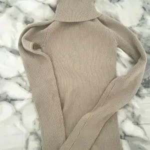 Säljer en supermysig beige polotröja i ribbat material. Perfekt för kyliga dagar med sin långa ärmar och höga krage. Tröjan är både stilren och bekväm, idealisk för höst och vinter. Passar perfekt till jeans eller kjol för en avslappnad look.