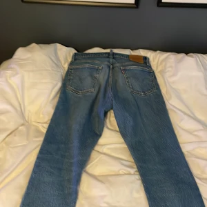 Blå jeans från Levi's 501 - Säljer ett par klassiska blå jeans från Levi's i bra skick. De har en straight passform och är perfekta för vardagsbruk. Jeansen har en knappgylf och fem fickor. Perfekta för både höst och vår!