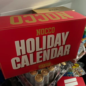 NOCCO ADVENTSKALENDER 2024 - Säljer en NOCCO Holiday Calendar (oanvänd) i en snygg röd förpackning. Denna limited edition-kalender innehåller 24 burkar med olika smaker. Perfekt för att räkna ner dagarna till jul med en ny överraskning varje dag. Förpackningen är stilren och passar perfekt som present till någon som älskar NOCCO.