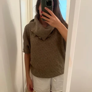 Beige stickad tröja med knappar - Säljer en supermysig beige stickad tröja med en stor krage och dekorativa knappar. Perfekt för höst och vinter! Tröjan har korta ärmar och ett diskret mönster som ger den en extra touch. Den är både stilren och bekväm, perfekt för kyliga dagar. 🧶✨