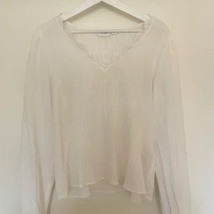 Vit långärmad topp från Vila - Säljer en superfin vit långärmad blus från vero moda i märket Vila i storlek 38. Den har en vacker spetsdetalj vid den v-ringade halsen , lyftig och ett subtilt mönster i tyget (se bild). Perfekt för både vardag och fest! Blusen är helt oanvänd och i nyskick. Skulle säga att storleken är en S/M och sitter väldigt fint på. Nypris är 499 och säljer för 120 men pris kan diskuteras 