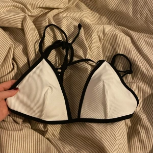 Vit och svart bikiniöverdel - aldrig använd, strl s/xs🙌 Snygg vit bikiniöverdel med svarta kanter och knytband. Perfekt för sommardagar på stranden eller vid poolen. Den har en enkel och stilren design som passar till det mesta. Materialet känns bekvämt och lätt mot huden. Ett måste för din badgarderob!