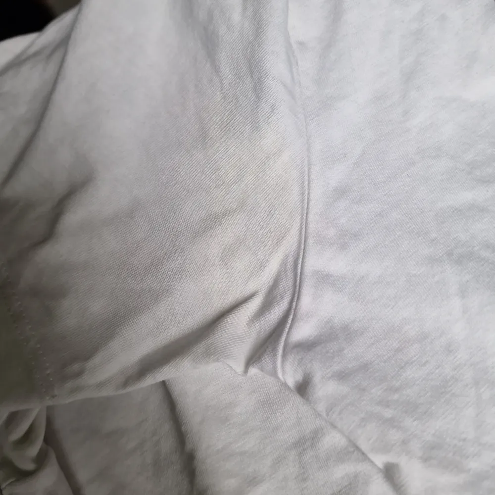 Säljer en klassisk vit t-shirt från Levi's i bomull. Den har en röd logga på framsidan och i bra skick (förutom knappt synliga fläckar, se bild) Perfekt för en avslappnad stil eller som basplagg i garderoben. Kortärmad och normal passform.. T-paidat.