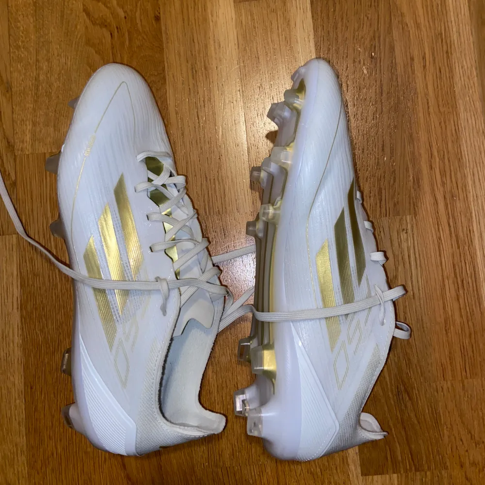 Säljer ett par snygga vita fotbollsskor med guldiga detaljer. De har snörning och är i mycket bra skick. Perfekta för fotbollssäsongen! Adidas F50 pro FG Day Spark - vit/guld. Skor.