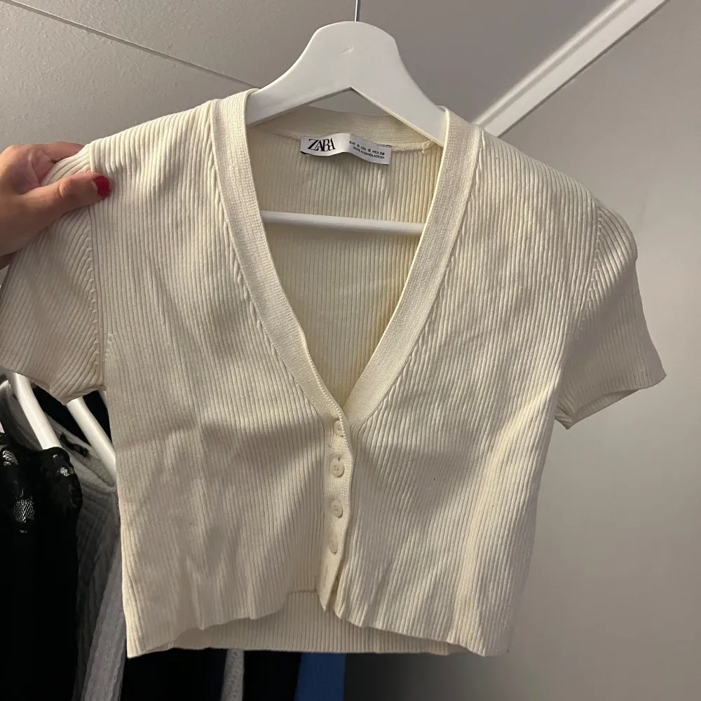 Säljer en superfin beige ribbad topp från Zara i storlek S. Den har en v-ringad design med knappar framtill och korta ärmar. Toppen är i bra skick. Säljer för 60kr + frakt🥰. Toppar.