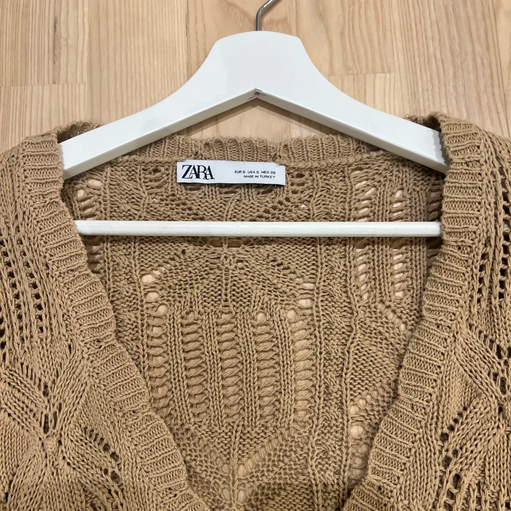 Säljer en superfin beige stickad kofta från Zara. Den har en v-ringad design med knytning framtill och långa ärmar med volangdetaljer. Perfekt för höst och vår när du vill ha något både snyggt och bekvämt. 🧶✨. Tröjor & Koftor.