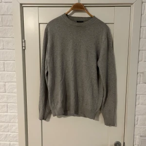 Grå ulltröja från Massimo Dutti - Säljer en stilren grå tröja från Massimo Dutti i ull. Perfekt för kyliga dagar med sin mjuka och varma känsla. Tröjan har en klassisk rund hals och ribbade muddar vid ärmslut och nederkant. Passar både till vardags och lite finare tillfällen.